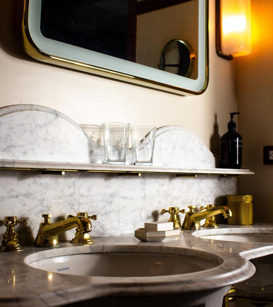 Marble vanity with arched backsplash and brass fixtures at The Driskill Hotel