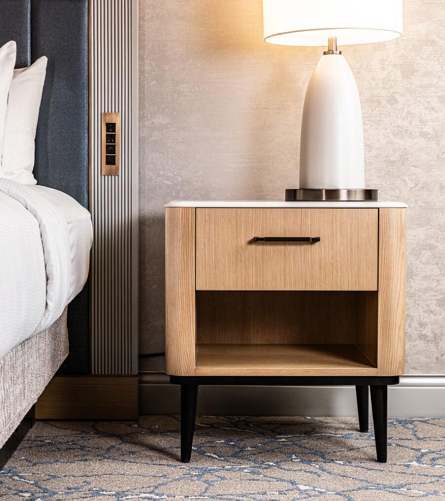 Hospitality night stand next to a bed in the Hilton Anatole hotel