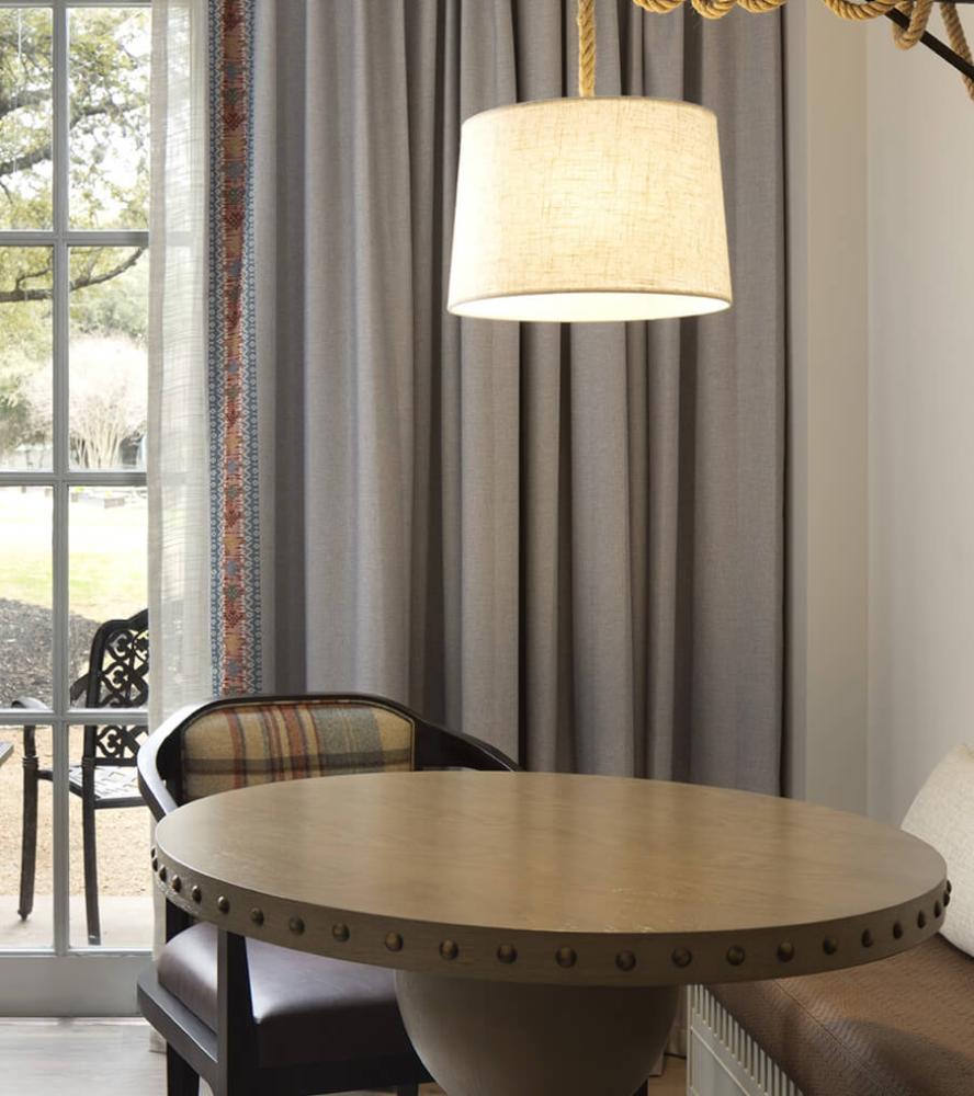 A round oak table sitting under a beautiful lamp at Hyatt Regency Hill Country hotel