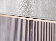 A close up shot of a bed headboard with fine detailing including leather and metal insets