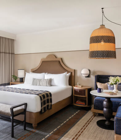A hotel room showing bed, sofa and side table in bright sunlight